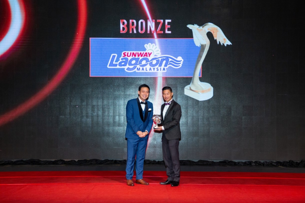 A full landscape photo of Sunway Theme Parks executive director Calvin Ho receiving the Putra Bronze award on stage for the category of Entertainment.