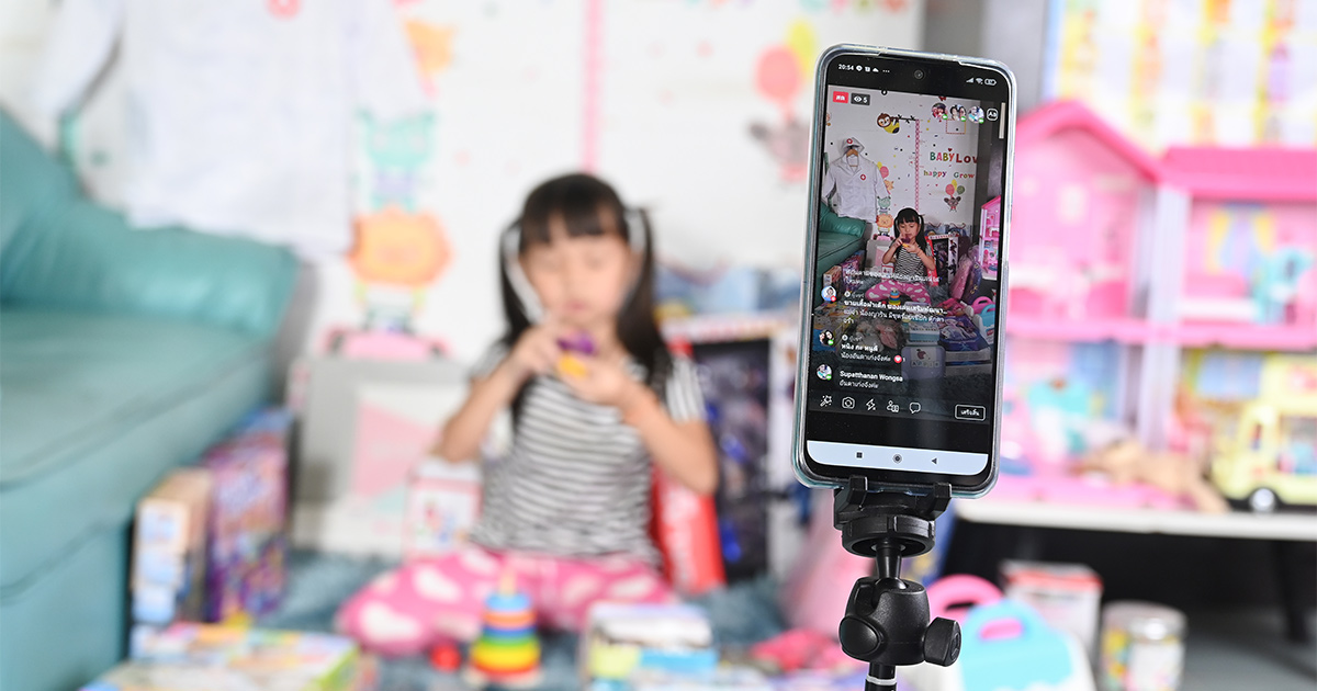 A shot of a phone with a TikTok livestream of a little girl, who is playing with her pink toys.