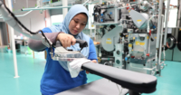 A medium landscape shot of a Sunway Pristine Laundry staff carefully ironing a garment using a Sankosha industrial steam press iron machine.