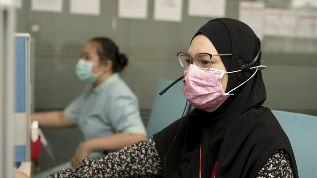 A masked attendee working Sunway Telemedicine Command Centre, with a nurse in the background
