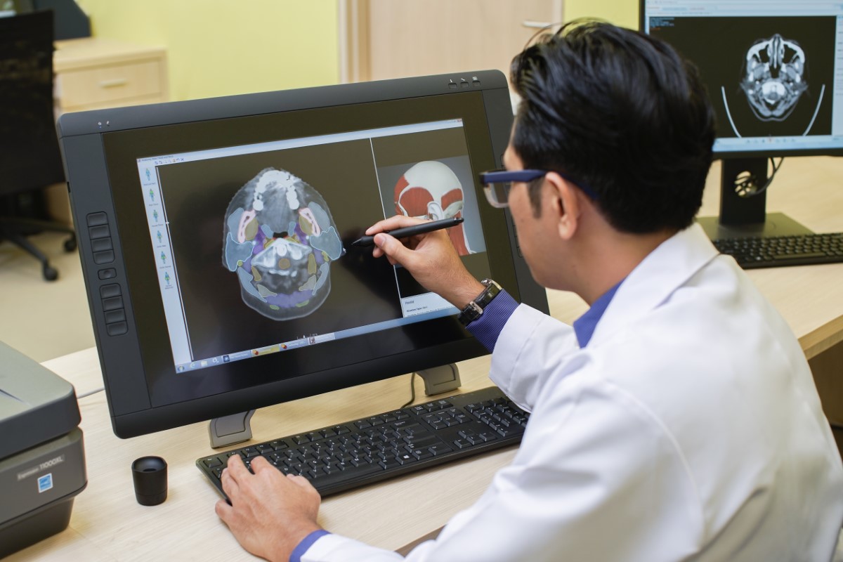 A medical doctor doing work on a patient on a computer.