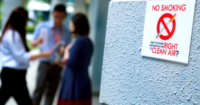 A No Smoking Sign on a grey wall at Sunway Leadership Centre in Menara Sunway, with three staff in the background.