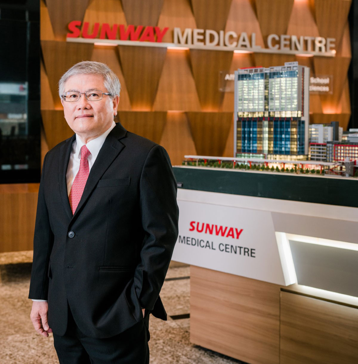 A mid-shot of Dato’ Lau Beng Long, with the 3D model of Sunway Medical Centre in the background