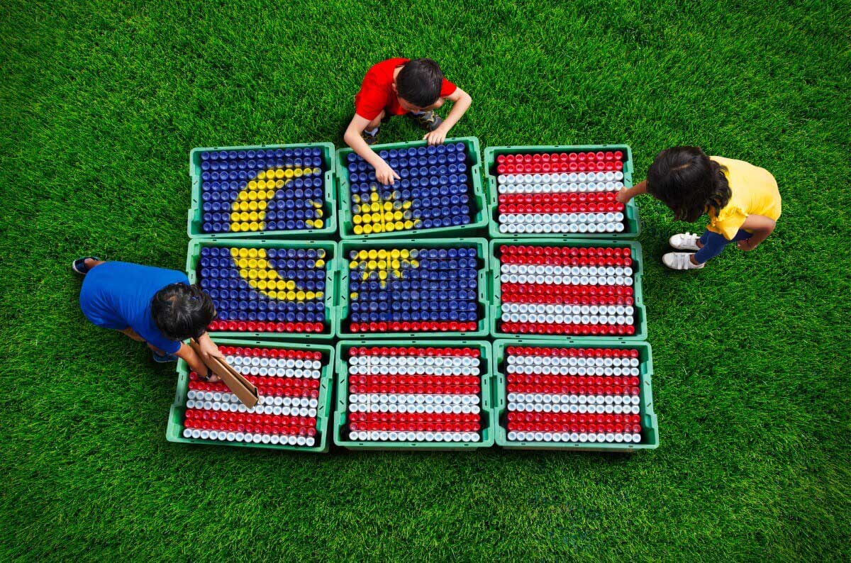 Photo of kids arranging coloured plastic bottles to create a Malaysian flag.