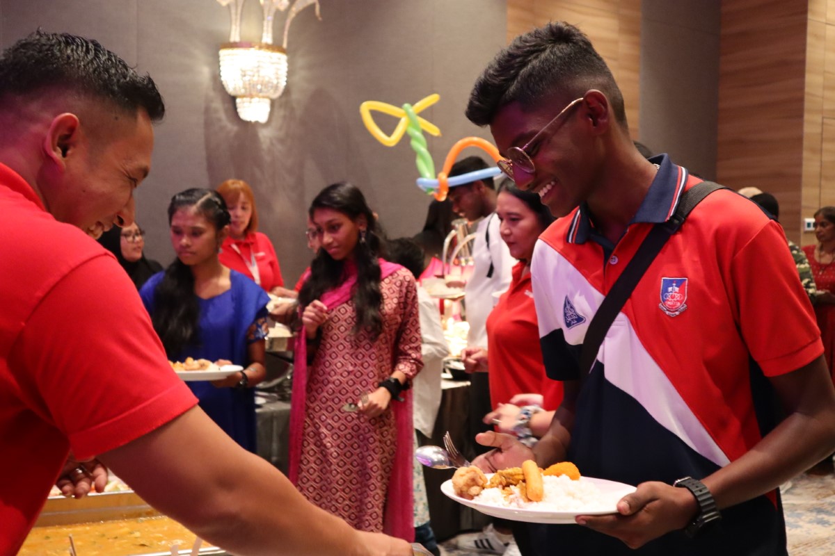 A child smiling as food is being served to them by a Sunway staff