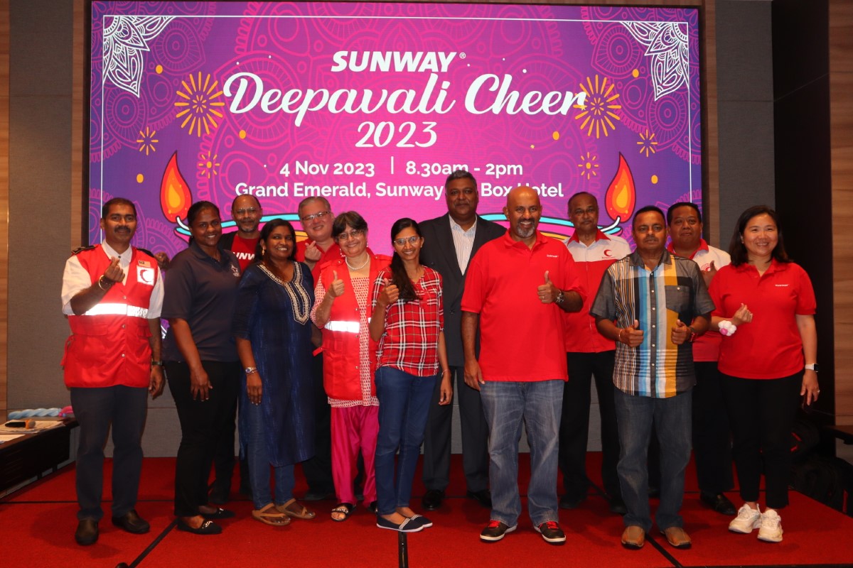 A photo of Sunway staff posing in front of the Sunway Deepavali cheer banner
