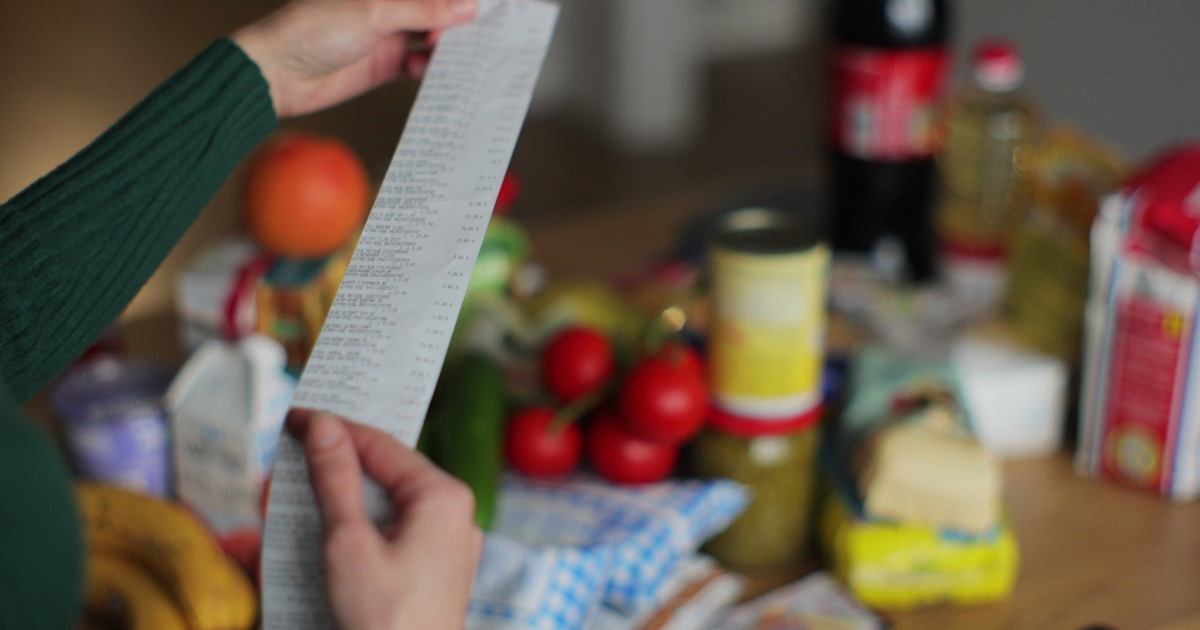 mid-shot of a woman holding a receipt, with groceries in the background