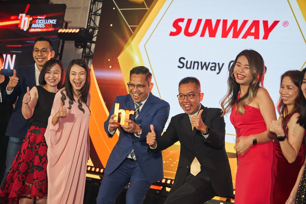 Sunway staff receiving the HR Excellence Awards trophy and giving their thumbs up in 2023.