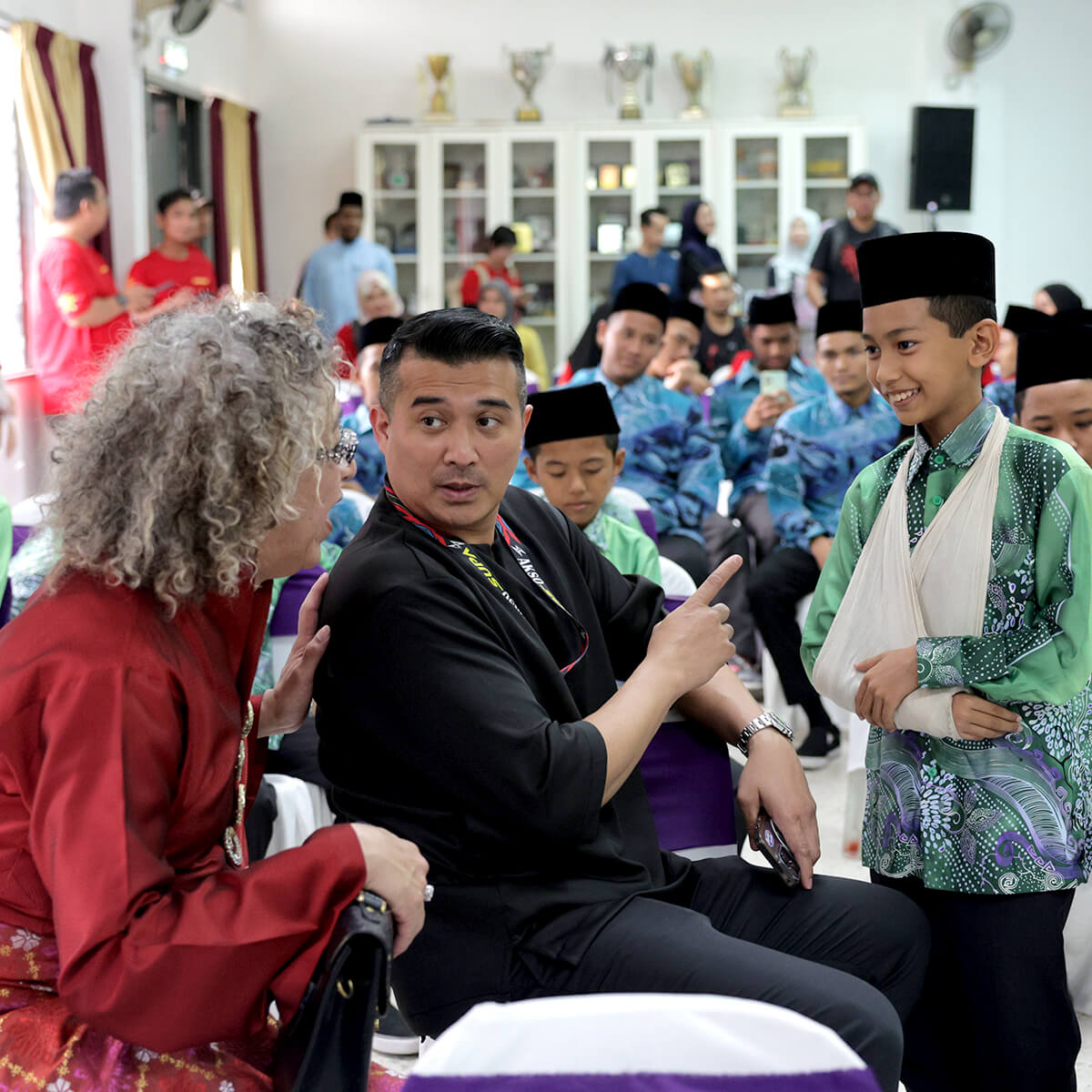 A mid-shot of Dato’ Aaron Aziz and Dee having a conversation with a child